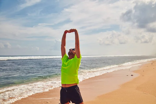 Deportista estirándose en una playa de arena tropical . — Foto de Stock