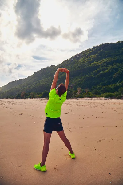 Esportista que se estende em uma praia tropical de areia . — Fotografia de Stock