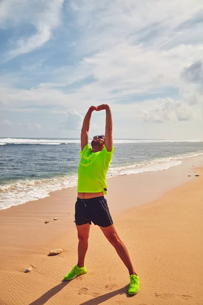 Deportista estirándose en una playa de arena tropical . — Foto de Stock