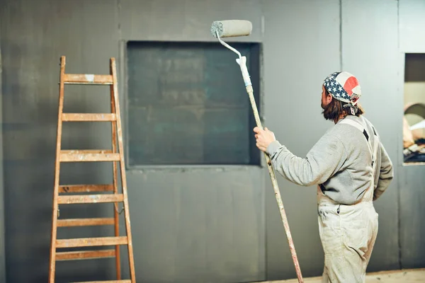 Maler streicht Wände mit einem Streckwalzen im Innenraum. — Stockfoto