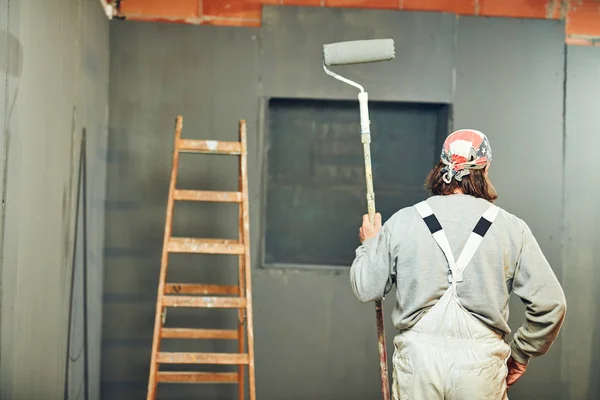 Pintor pintando paredes con un rodillo extensor en interiores . — Foto de Stock