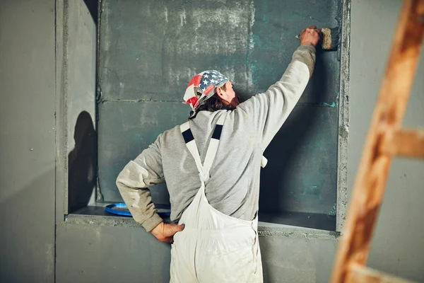 Pintor pintando paredes con un pincel en interiores . — Foto de Stock