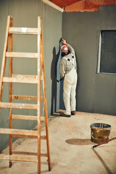 Pintor pintando paredes con un pincel en interiores . — Foto de Stock