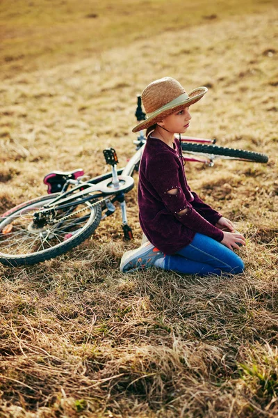 Bonito menina de dez anos com bicicleta no prado do campo — Fotografia de Stock