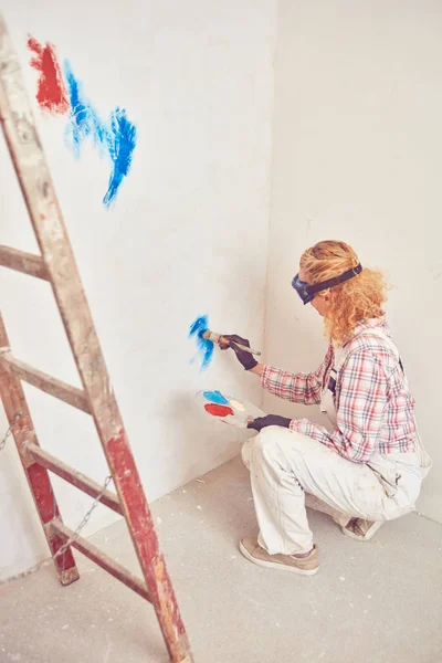Working woman plastering / painting walls inside the house.