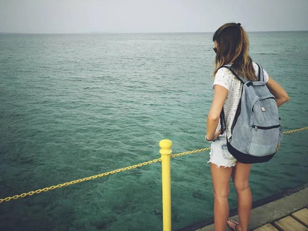 Mujer soltera cerca del océano / mar en un muelle de madera . — Foto de Stock