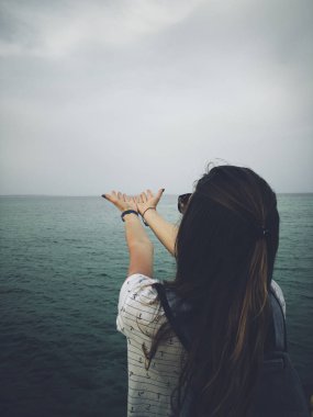 Deniz kıyısında dua eden kolları olan kadın.