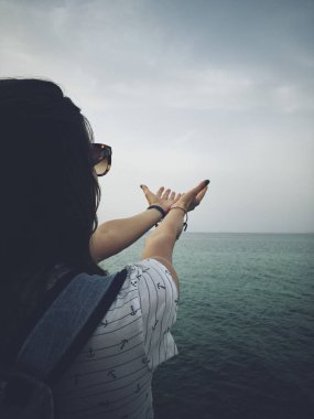 Deniz kıyısında dua eden kolları olan kadın.