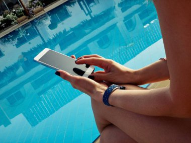 Yüzme havuzu yakınında cep telefonu kullanan genç kadın.