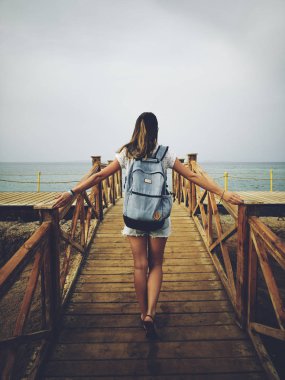 Ahşap bir iskelede okyanus / deniz yakınında tek kadın.