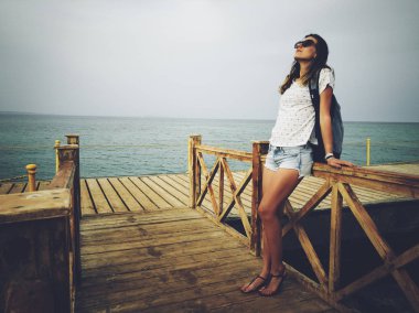 Ahşap bir iskelede okyanus / deniz yakınında tek kadın.