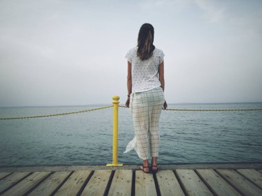 Yalnız kadın bir deniz / okyanus kıyısında ayakta.