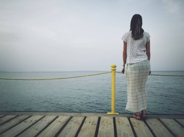 Yalnız kadın bir deniz / okyanus kıyısında ayakta.