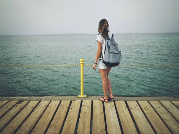 Alleinstehende Frau in der Nähe des Meeres / Ozeans auf einem Holzsteg. — Stockfoto