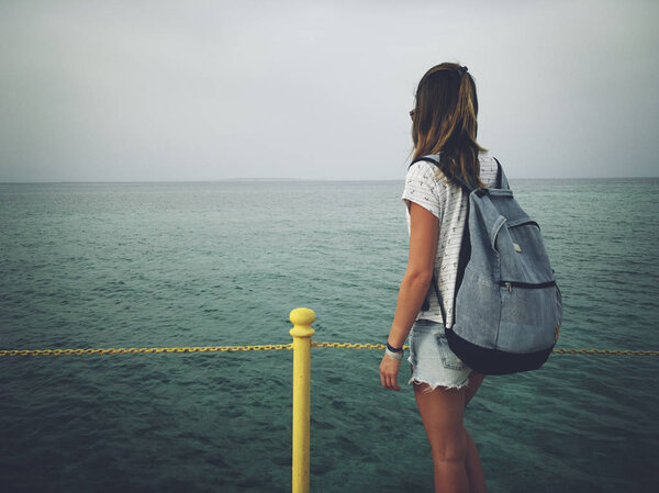 Single woman near the ocean / sea on a wooden pier.