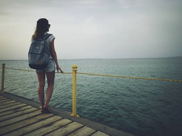 Mujer soltera cerca del océano / mar en un muelle de madera . — Foto de Stock