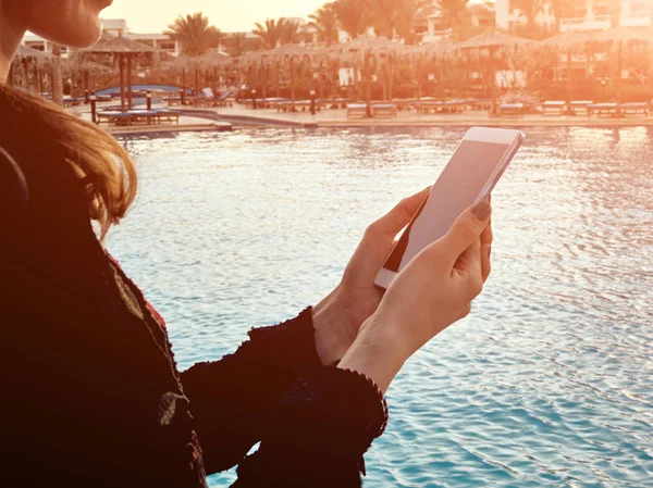 Mujer joven usando el teléfono celular cerca de la piscina . — Foto de Stock