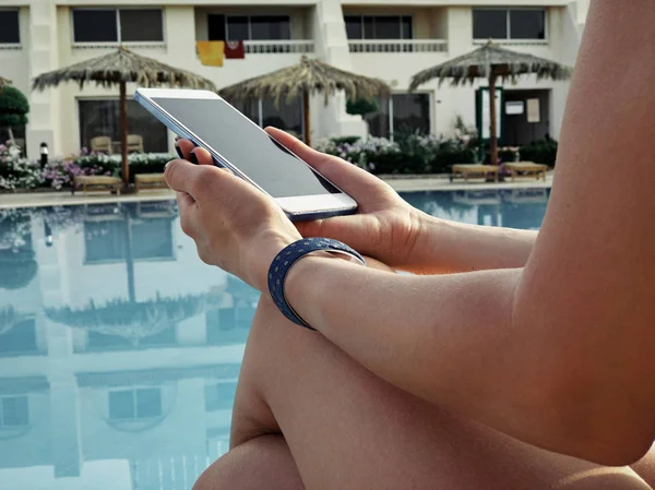 Молода жінка використовує мобільний телефон біля басейну . — стокове фото