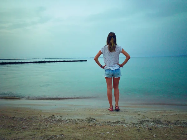 Samotna kobieta stojąca na morzu/brzegu oceanu. — Zdjęcie stockowe