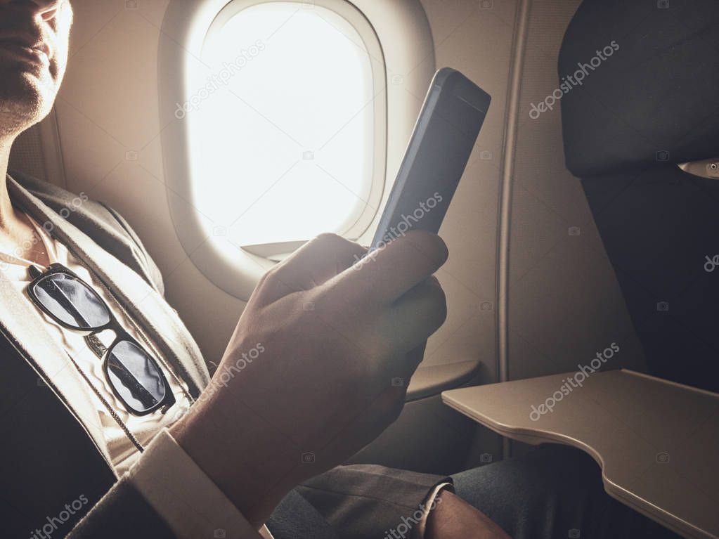 Man using smartphone in the airplane.