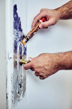 Handyman kapı etrafında kesel kullanarak eski boya TTO Scrub kilitleme.