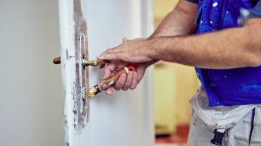 Handyman kapı etrafında kesel kullanarak eski boya TTO Scrub kilitleme.