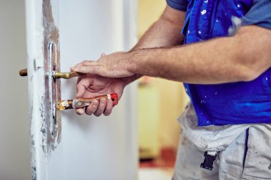 Handyman kapı etrafında kesel kullanarak eski boya TTO Scrub kilitleme.