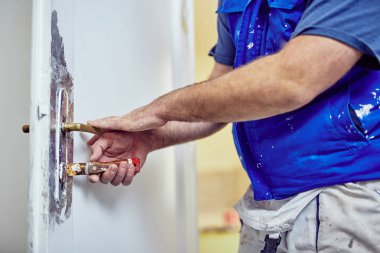 Handyman kapı etrafında kesel kullanarak eski boya TTO Scrub kilitleme.