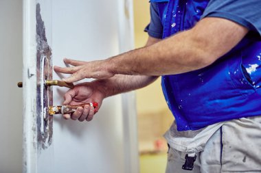 Handyman kapı etrafında kesel kullanarak eski boya TTO Scrub kilitleme.