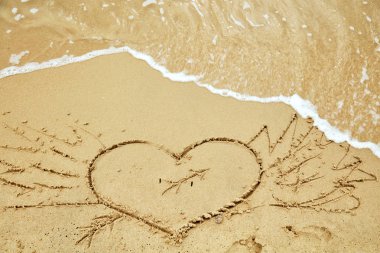 Yaz aylarında kumlu bir plajda kalp şeklinde sembol.