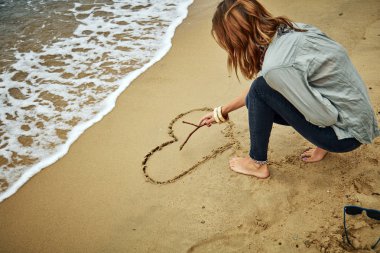 Bir kalp okyanus kuma çizim kız / deniz plaj.