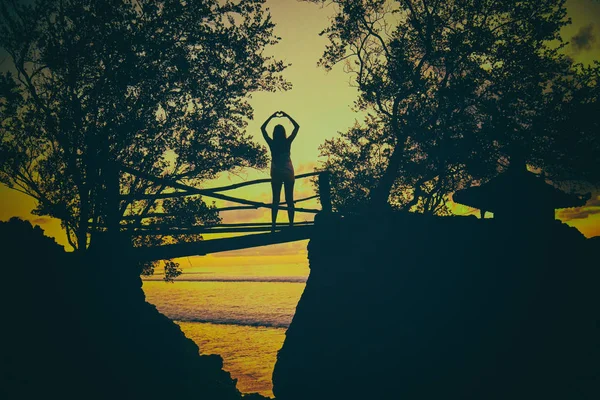 Silhouette einer Frau bei Sonnenuntergang / Sonnenaufgang mit tropischer Sonne — Stockfoto