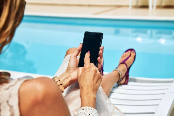 Молода жінка використовує мобільний телефон біля басейну . — стокове фото