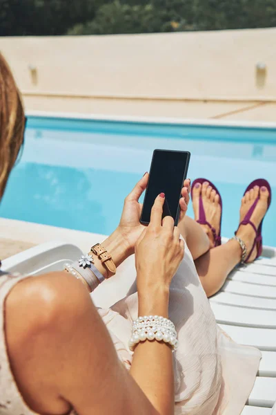 Jonge vrouw het gebruik van mobiele telefoon in de buurt van het zwembad. — Stockfoto