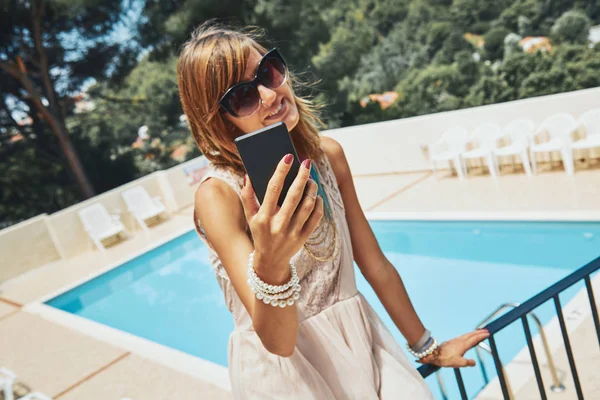 Χαριτωμένο νεαρή γυναίκα χρησιμοποιώντας κινητό τηλέφωνο κοντά στην πισίνα. — Φωτογραφία Αρχείου