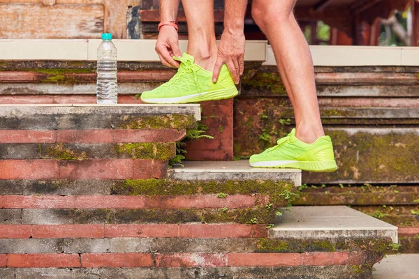 Sportsman making a pause and tying running shoes.