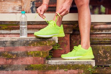 Sporcu bir duraklama yapma ve koşu ayakkabıları bağlama.