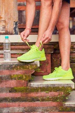 Sporcu bir duraklama yapma ve koşu ayakkabıları bağlama.