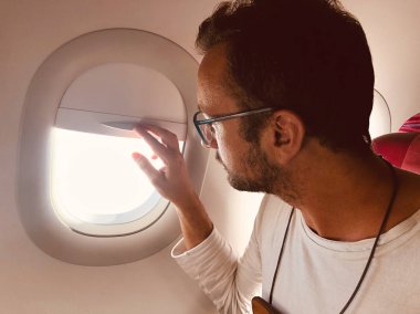 Pencerenin yanındaki modern uçak koltuğundaki yolcu.