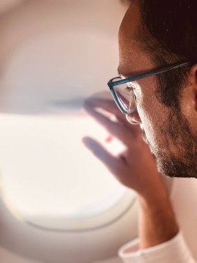 Pencerenin yanındaki modern uçak koltuğundaki yolcu.