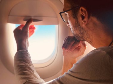 Pencerenin yanındaki modern uçak koltuğundaki yolcu.