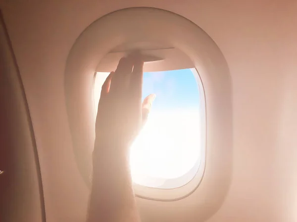 Ręka pasażera zamykająca cień okna na nowoczesnym samolocie. — Zdjęcie stockowe