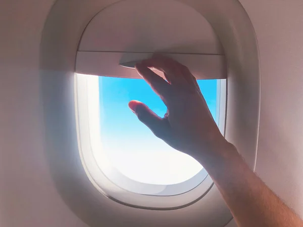 Die Hand des Passagiers beim Schließen des Fensterschirms in einem modernen Flugzeug. — Stockfoto