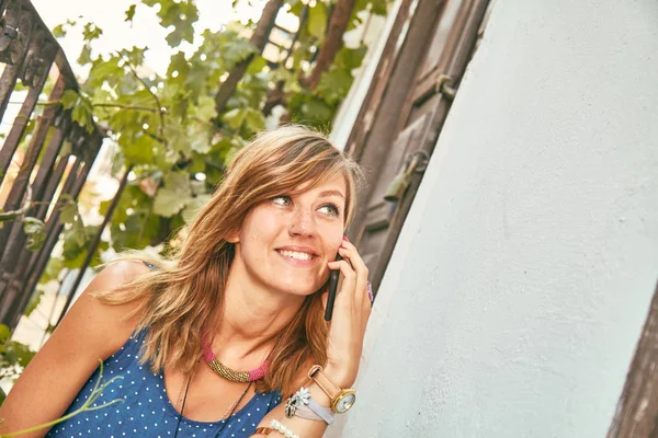 Carino giovane donna utilizzando il cellulare sul portico / terrazzo di casa . — Foto Stock