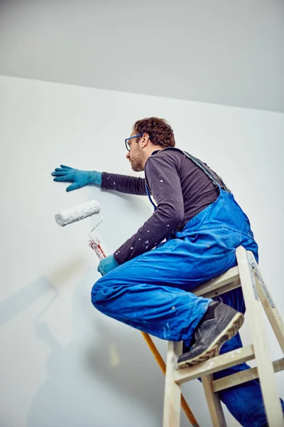 Arbeiter streicht Wände im Haus - Renovierung repariert. — Stockfoto