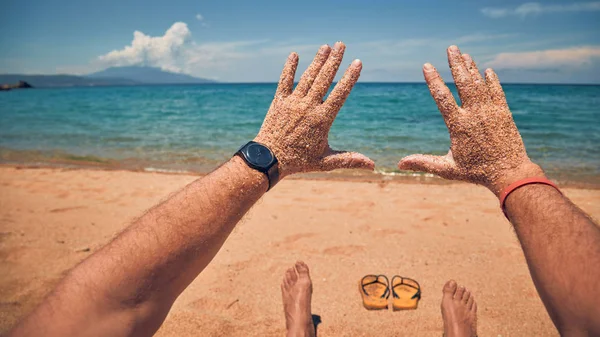 Man playing with his hands on a sandy tropical beach.