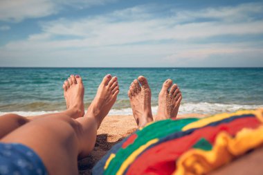 Çiftler kumlu bir plajda uzanıp eğleniyorlar..