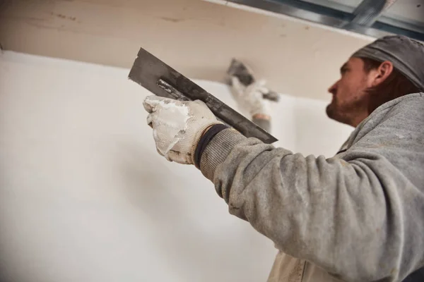 Работник оштукатурирует гипсовые стены внутри дома . — стоковое фото