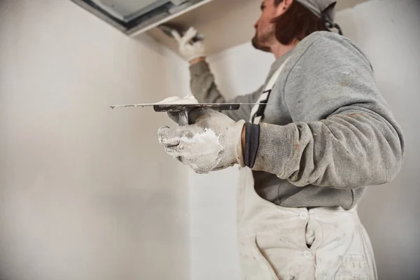 Работник оштукатурирует гипсовые стены внутри дома . — стоковое фото