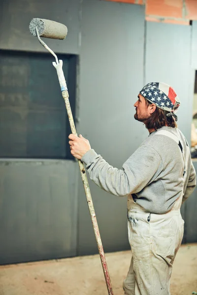 Peintre peinture murs avec un rouleau extenseur à l'intérieur . — Photo